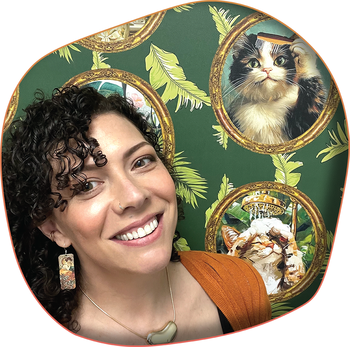An image of a woman smiling with cat-themed wallpaper in the background.